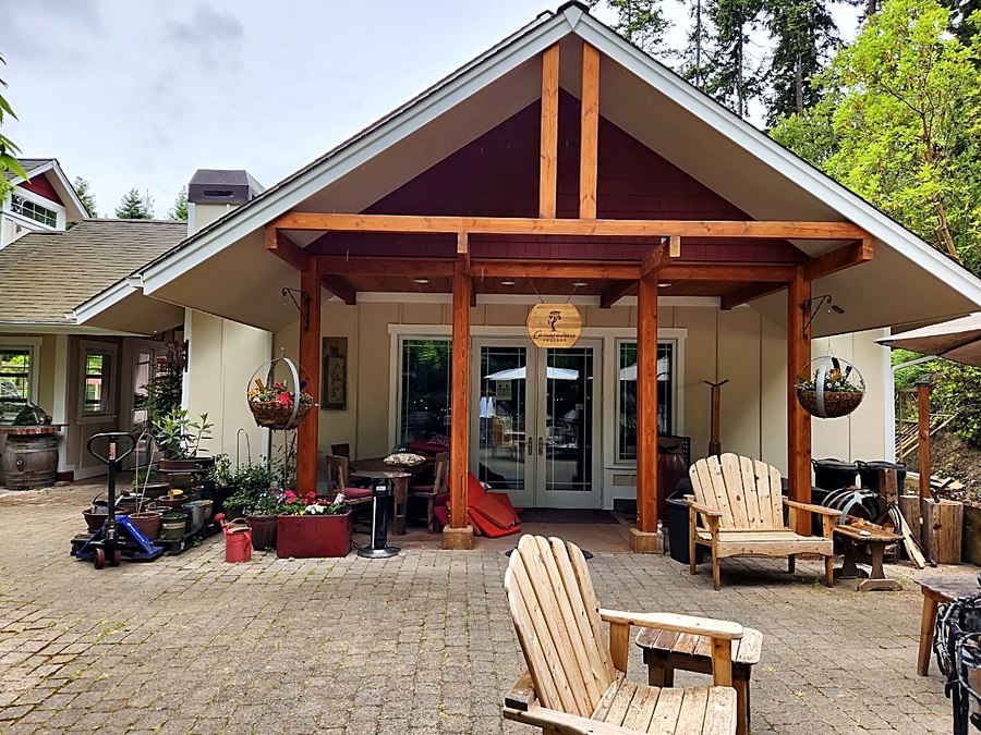 Timber-framed covered entry with cedar posts and beams, cream siding and deep red gable shingles, finished by Painters Plus.